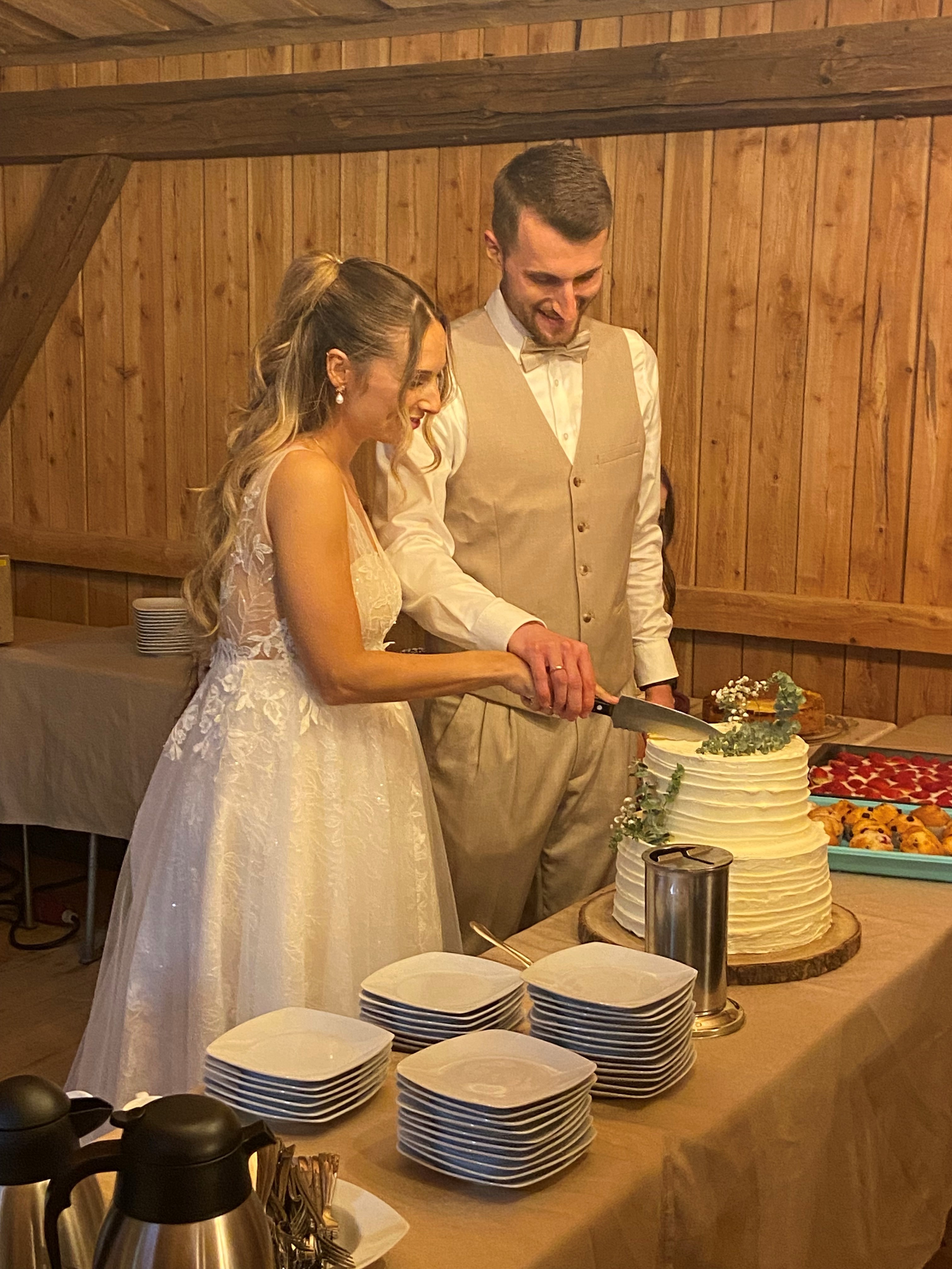 Brautpaar beim Anschneiden der Hochzeitstorte in der Festscheune